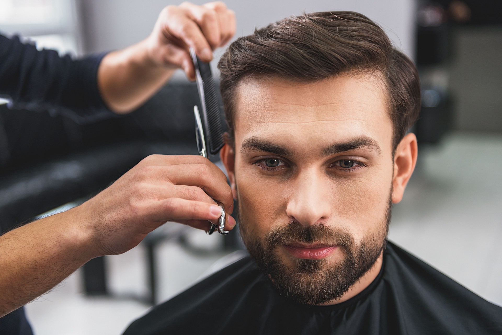 Skillful hairdresser cutting male hair